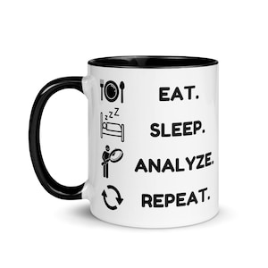Peut inclure: Mug en céramique blanche avec un bord noir. Le mug a du texte noir et des icônes qui disent "EAT. SLEEP. ANALYZE. REPEAT."