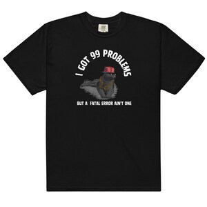 Puede incluir: Camiseta negra con un gráfico blanco de un gato con un sombrero rojo y una cadena de oro. El texto dice "Tengo 99 problemas, pero un error fatal no es uno."