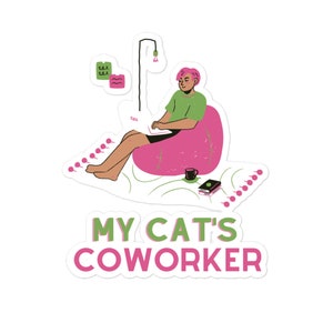 以下が含まれることがあります： ピンクのビーンバッグチェアに座って、ラップトップで作業をしている人がいます。その人はピンクの髪をしていて、緑のシャツを着ています。画像の下には「MY CAT'S COWORKER」というテキストがあります。