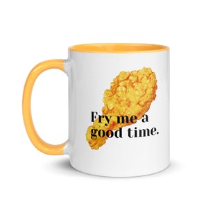 Może przedstawiać: Biały ceramiczny kubek z pomarańczowym wnętrzem i uchwytem. Kubek przedstawia grafikę smażonej nogi z kurczaka i napis "Fry me a good time."