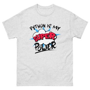 Puede incluir: Una camiseta gris con el texto "Python is my Super Power" en una fuente de estilo cómic. La palabra "Super" está en rojo y el resto del texto está en negro.