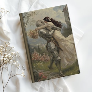 May include: A hardcover journal featuring a romantic medieval scene. The image depicts a knight in shining armor carrying a woman in a white dress. The cover has a gold border and a vintage aesthetic.