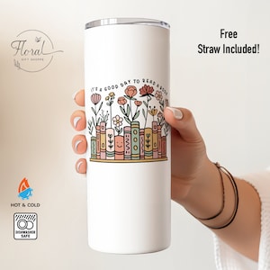 May include: White stainless steel tumbler with a floral design and the text "It's a good day to read a book".