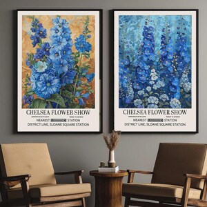 Può includere: Due stampe da parete incorniciate raffiguranti fiori di speronella blu. Ogni stampa riporta il testo CHELSEA FLOWER SHOW, NEAREST UNDERGROUND STATION e DISTRICT LINE, SLOANE SQUARE STATION. La stampa a sinistra ha uno sfondo dorato, quella a destra blu.