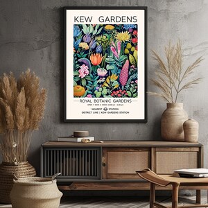 May include: A vintage-style poster advertising Kew Gardens, a Royal Botanic Gardens in London. The poster features a colorful illustration of various flowers and plants, with the text "Kew Gardens" and "Royal Botanic Gardens" in black lettering. The poster also includes information about the gardens' opening hours and the nearest Tube station.