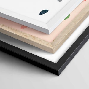 May include: Three picture frames stacked on top of each other. The top frame is white, the middle frame is light wood, and the bottom frame is black.