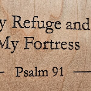 以下が含まれることがあります： 「My Refuge and My Fortress - Psalm 91」というテキストが刻まれた木製の看板です。