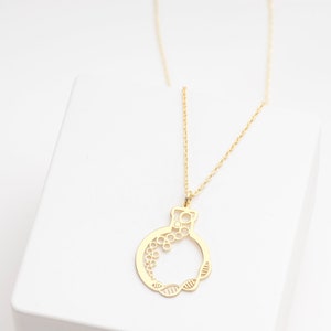 Può includere: Una collana d'oro con una catena delicata e un ciondolo a forma di cerchio con intricati tagli. Il ciondolo è in oro e presenta un design delicato e femminile.
