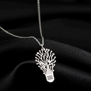 May include: A silver necklace featuring a light bulb pendant. The pendant is crafted from a delicate, intricate design that resembles a circuit board.