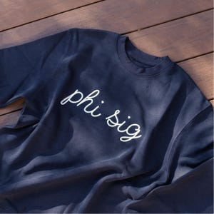 May include: A dark blue sweatshirt with white embroidered text that reads "phi sig".
