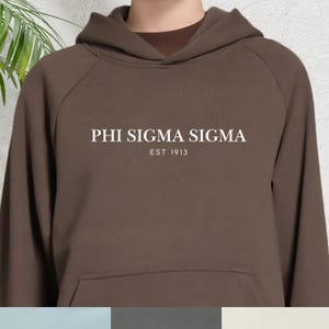 May include: A brown hooded sweatshirt featuring the white text "PHI SIGMA SIGMA EST 1913". The sweatshirt has a drawstring hood and a kangaroo pocket. The material looks soft and comfortable, suitable for casual wear.