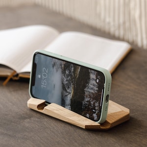 May include: A light green phone case with a wooden phone stand. The phone screen shows the time 15:02.