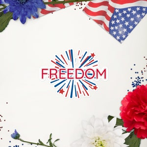 Könnte beinhalten: Ein Aufkleber mit dem Wort "FREEDOM" in Rot, weiß umrandet, mit einem Feuerwerksdesign in Rot und Blau. Das Bild enthält Blumen, eine amerikanische Flagge und sternförmige Konfetti.