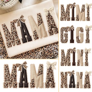 Op de afbeelding: Crèmekleurige stof met het woord "MAMA" geborduurd in een luipaardprint, geaccentueerd met een bruine letter "A" en een beige strik. Extra ontwerpen zijn onder meer "MIMI", "GIGI", "MINI" en "NANA" in vergelijkbare stijlen.