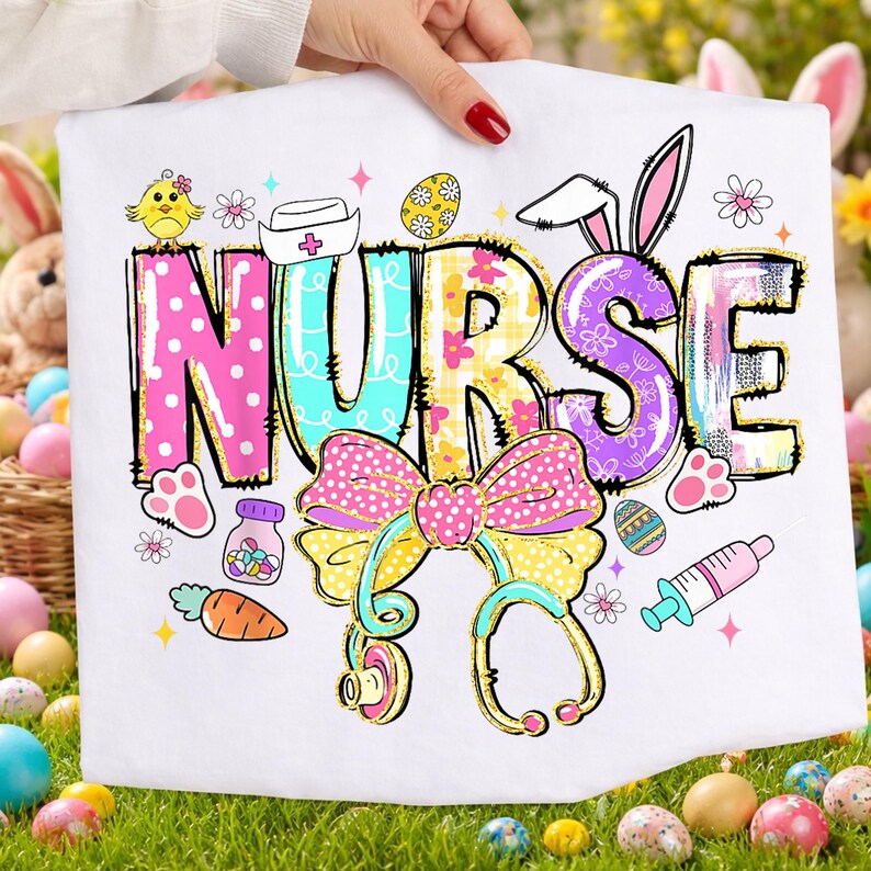 May include: White graphic tee with the word "NURSE" in colorful, decorative letters. The design includes Easter-themed elements like bunny ears, eggs, a bow, stethoscope, and a syringe. A cute chick and carrot are also included.