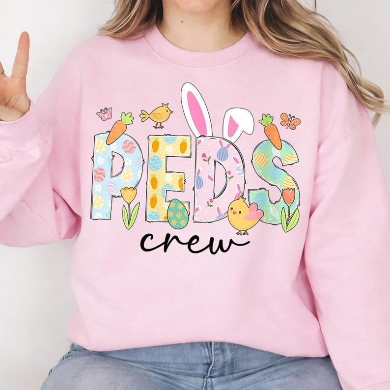 May include: Pink sweatshirt with the word "PEDS" in pastel colors, decorated with Easter-themed graphics. The word "crew" is written in black script below. Features include bunny ears, carrots, chicks, and eggs.