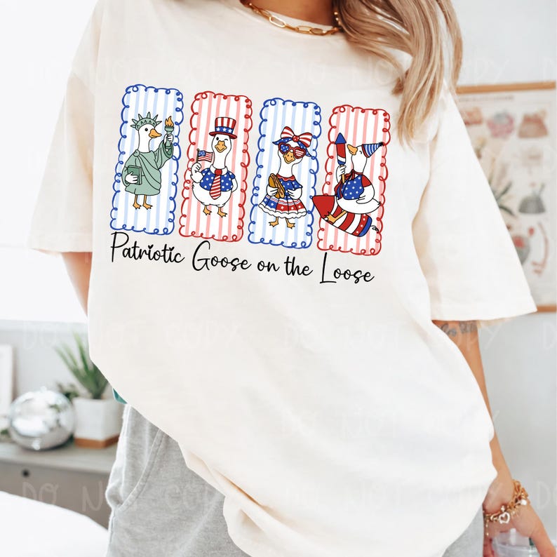 May include: Cream-colored t-shirt featuring a patriotic design with four cartoon geese in red, white, and blue outfits. Each goose is in a rectangular frame with a scalloped edge. The text "Patriotic Goose on the Loose" is below the geese.