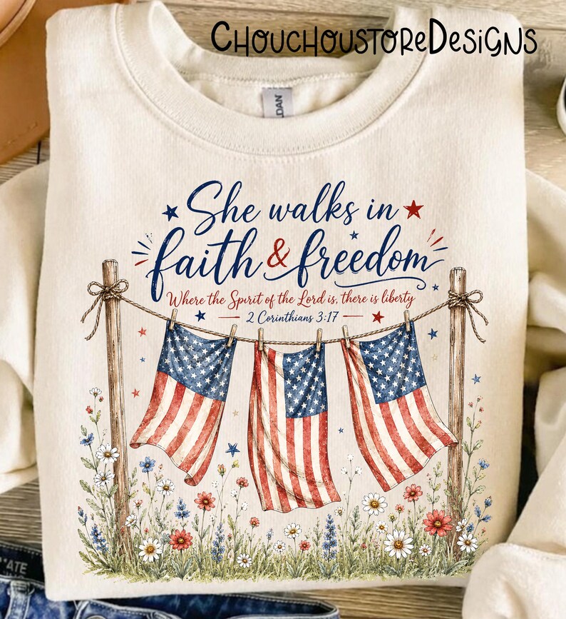 May include: Cream-colored sweatshirt with the text "She walks in faith & freedom" and American flag imagery. The design includes floral accents and the Bible verse 2 Corinthians 3:17.