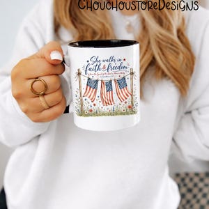 May include: White ceramic mug with a black interior rim, featuring the text "She walks in faith & freedom" and American flags. The design includes floral and patriotic elements, perfect for a gift.