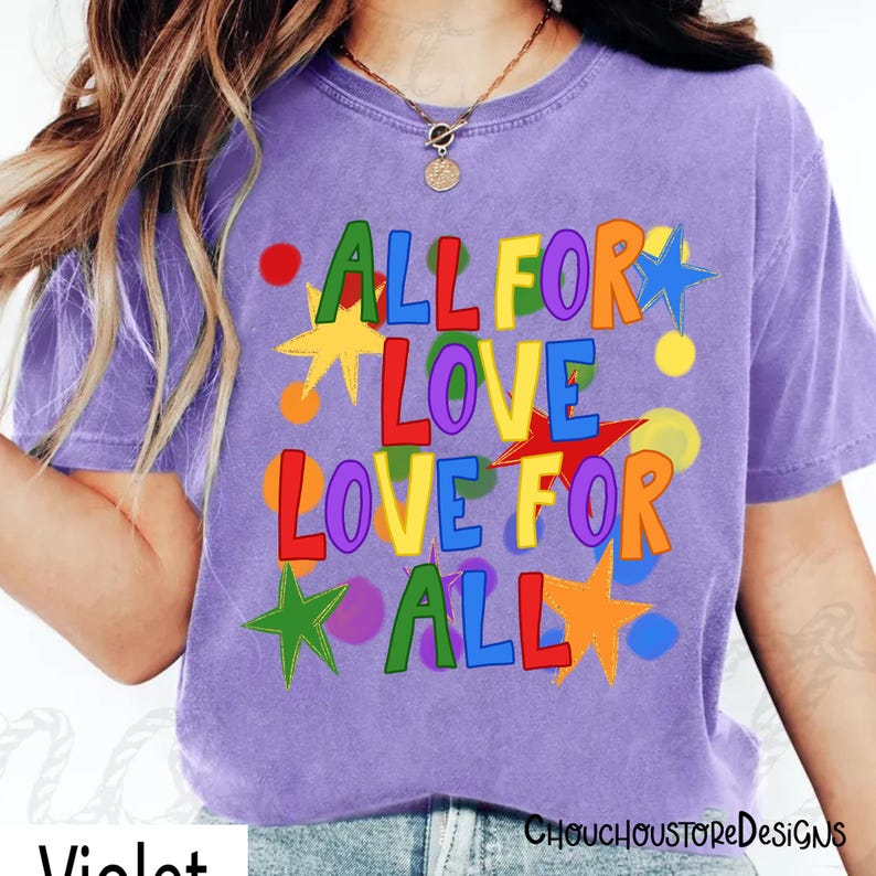 May include: A violet-colored t-shirt with the text "ALL FOR LOVE LOVE FOR ALL" in colorful letters and star shapes. The shirt has a crew neck and short sleeves. The design includes red, yellow, green, blue, and orange accents.
