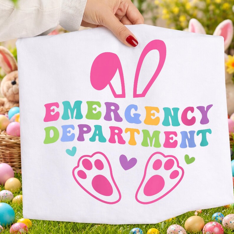 May include: A white Easter-themed towel with the words "EMERGENCY DEPARTMENT" in colorful letters. The towel features pink bunny ears, paw prints, and hearts. The towel is held up by a person with red nail polish.