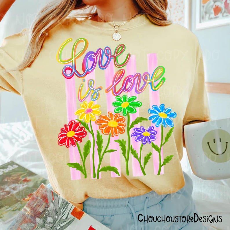 K&ouml;nnte beinhalten: Hellgelbes T-Shirt mit dem Schriftzug "Love is Love" in farbenfroher Schrift &uuml;ber einer Reihe von Regenbogenblumen. Die Blumen sind vor rosa vertikalen Streifen platziert. Das T-Shirt hat kurze &Auml;rmel.