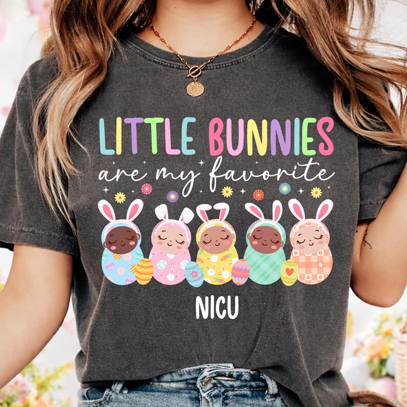 May include: Dark gray t-shirt with the text "LITTLE BUNNIES are my favorite" in colorful letters. Below the text are five baby bunnies in Easter outfits, each holding an Easter egg. The word "NICU" is printed below the bunnies.