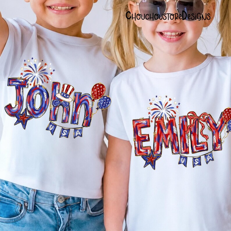 Puede incluir: Dos camisetas blancas con dise&ntilde;os patri&oacute;ticos. Una camiseta presenta el nombre "John" en rojo, blanco y azul, con una estrella, globos y una pancarta que dice "USA". La otra camiseta dice "Emily" en un estilo similar, con fuegos artificiales y un lazo.
