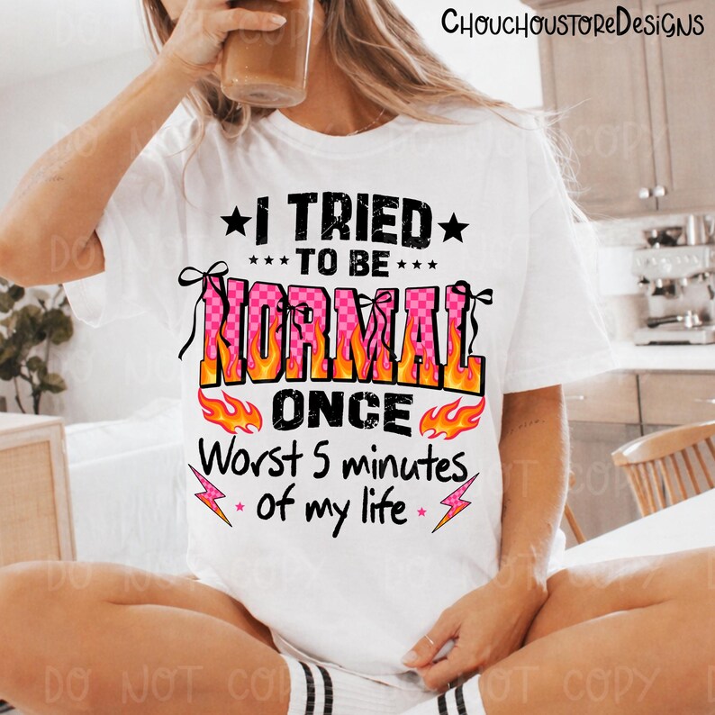 May include: White t-shirt with the text "I TRIED TO BE NORMAL ONCE Worst 5 minutes of my life" in black, pink, and orange. The word "NORMAL" is in a pink checkerboard pattern with flames. The shirt has a crew neck.