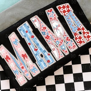 May include: A black surface displaying the word "MAMA" in decorative letters. Each letter has a different patriotic design, with bows, flowers, and stars in red, white, and blue. The letters are edged with a pearl-like border.