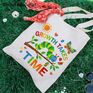 Puede incluir: Una bolsa de mano de lona blanca con una colorida ilustraci&oacute;n de una oruga, una mariposa y el texto "GROWTH TAKES TIME". El dise&ntilde;o incluye un sol, corazones y piezas de rompecabezas. La bolsa tiene asas de color crema.