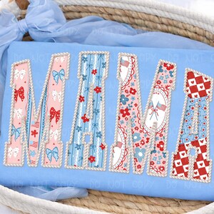 May include: A light blue cushion featuring the word "MAMA" in a patriotic design. Each letter is filled with a different pattern, including bows, flowers, and stars, and is outlined with pearls.