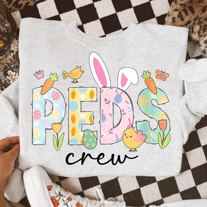 May include: A light gray sweatshirt with the word "PEDS" in colorful, patterned letters, with bunny ears and the word "crew" below. The design includes carrots, chicks, butterflies, and Easter eggs.
