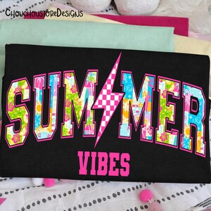 May include: Black t-shirt with the words "SUMMER VIBES" in a pink, collegiate-style font. The word "SUMMER" is filled with a colorful tropical pattern, and a pink and white checkered lightning bolt is in the center.