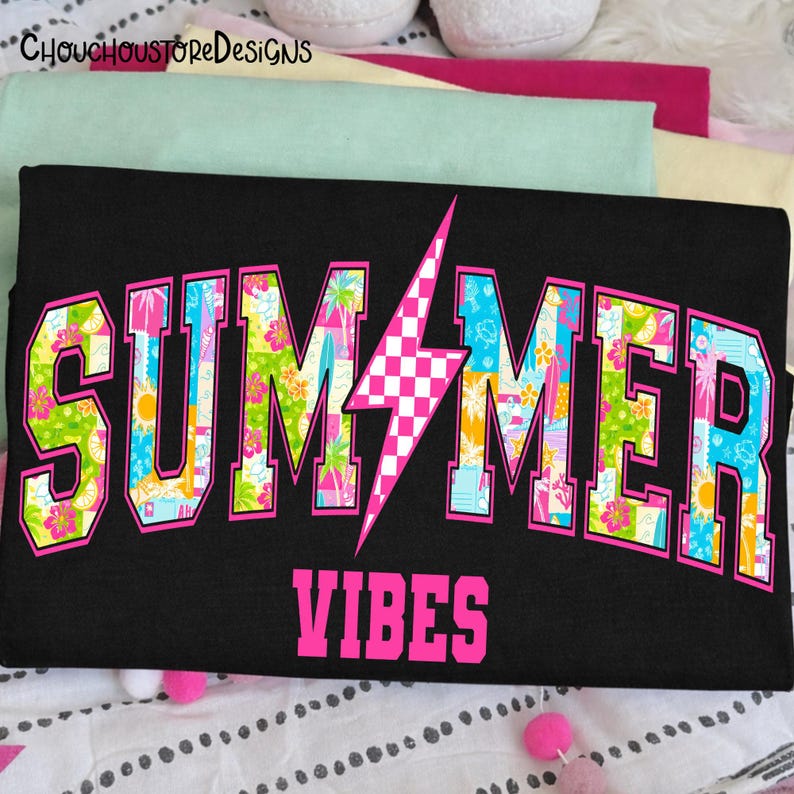May include: Black t-shirt with the words "SUMMER VIBES" in a pink, collegiate-style font. The word "SUMMER" is filled with a colorful tropical pattern, and a pink and white checkered lightning bolt is in the center.
