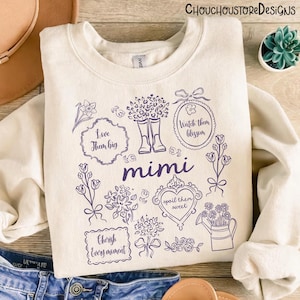 May include: Cream-colored sweatshirt with a purple floral design and the word "mimi". The design includes boots, flowers, and phrases like "Love them big" and "Cherish every moment". The brand name "Chouchoustore Designs" is at the top.
