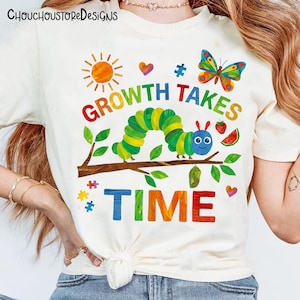 Puede incluir: Camiseta color crema con un gr&aacute;fico colorido. El dise&ntilde;o incluye una oruga, una mariposa, un sol y piezas de rompecabezas, con el texto "GROWTH TAKES TIME." La camiseta es de cuello redondo.