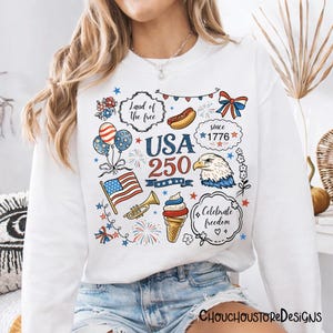 Puede incluir: Sudadera blanca con un colorido dise&ntilde;o gr&aacute;fico USA 250. El dise&ntilde;o incluye una bandera estadounidense, un &aacute;guila, fuegos artificiales y los textos "Land of the free" y "Celebrate freedom".