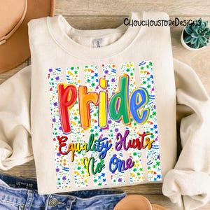 May include: Cream-colored sweatshirt with the word "Pride" in rainbow colors, and the phrase "Equality Hurts No One." The design is set against a floral and striped background. The sweatshirt is folded.