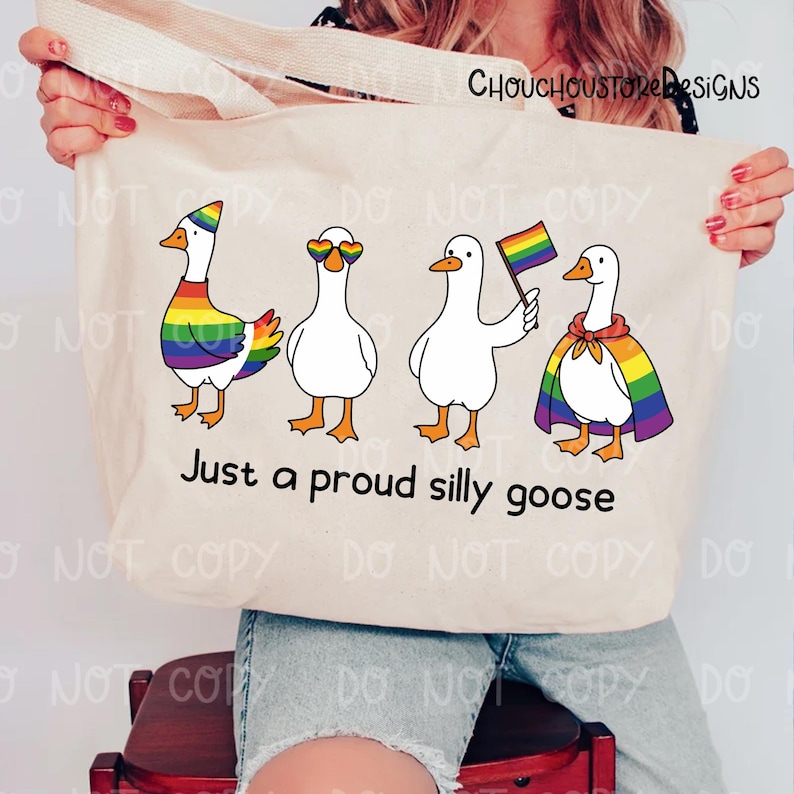 K&ouml;nnte beinhalten: Cremefarbene Tragetasche mit vier Cartoon-G&auml;nsen, jeweils mit Regenbogen-Details und Accessoires. Der Text "Just a proud silly goose" steht darunter. Die Tasche hat einen cremefarbenen Griff.