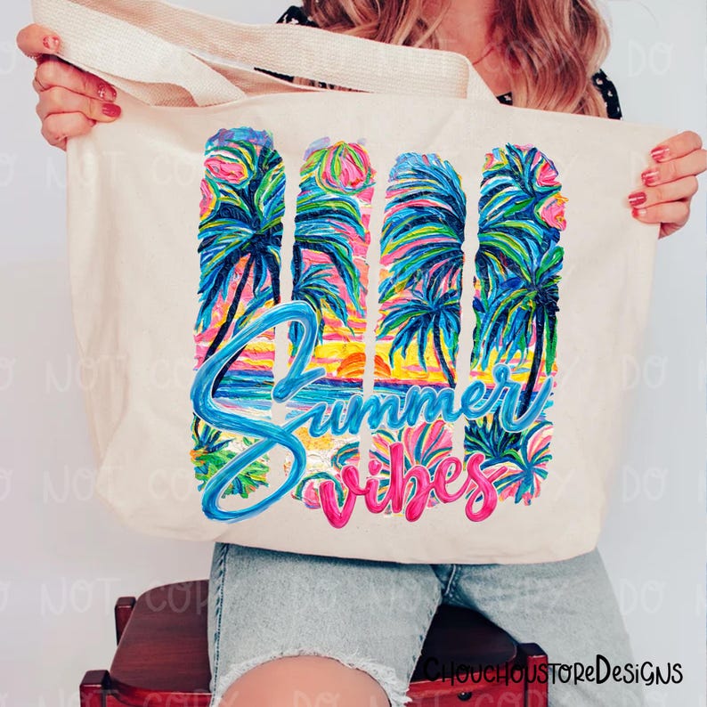 May include: A cream-colored tote bag with a colorful tropical design. The design features palm trees, a sunset, and the words "Summer Vibes" in blue and pink. The bag is held up by a person.