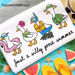 May include: White beach towel featuring cartoon geese in summer attire. One goose wears sunglasses and a flamingo float, another has a flower and coconut drink, a third has a snorkel and life vest, and the last wears a Hawaiian shirt. Text reads "Just a silly goose summer."