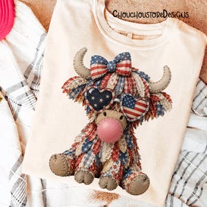 May include: Cream-colored t-shirt featuring a patriotic Highland cow design. The cow is adorned with a red, white, and blue patchwork pattern, heart-shaped sunglasses with American flag and star designs, and a bow. The text "ChouchoustoreDesigns" is printed on the shirt.