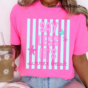 May include: Bright pink t-shirt with the text "SAY LESS IT'S summer break" in pink and light blue. The design includes light blue vertical stripes and pink stars. The shirt is a casual summer wear item.