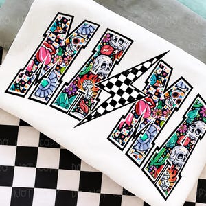 May include: White sweatshirt with the word "MAMA" in a bold, stylized font. Each letter is filled with colorful illustrations including skulls, flowers, dice, and lips. The design has a black outline and a checkered pattern.