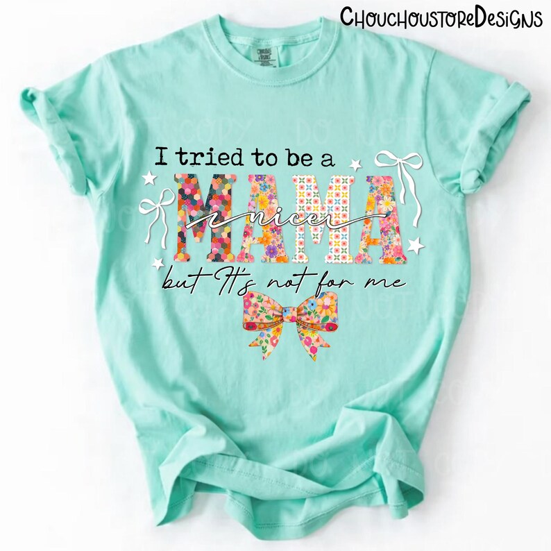May include: A light turquoise t-shirt with the text "I tried to be a nicer Mama but It's not for me." The word "MAMA" is filled with a floral pattern. A floral bow is at the bottom of the shirt.