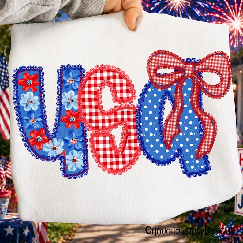 May include: White fabric with the text "USA" in red, white, and blue. The letter "U" is blue with red and white flowers, the "S" is red gingham, and the "A" is blue with white polka dots and a red gingham bow. The design is trimmed with lace.