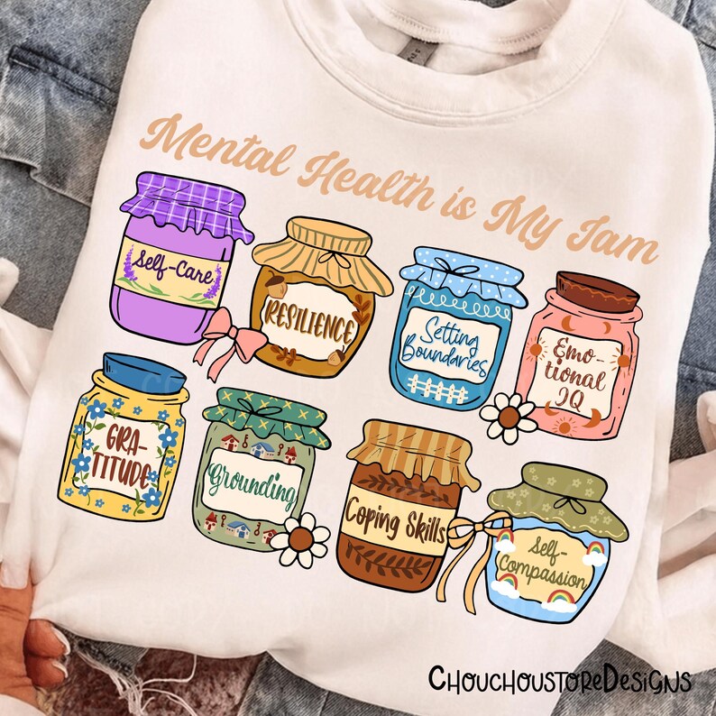 May include: White sweatshirt with the text "Mental Health is My Jam." Features illustrations of jam jars labeled "Self-Care," "Resilience," "Setting Boundaries," "Emotional IQ," "Gratitude," "Grounding," "Coping Skills," and "Self-Compassion."