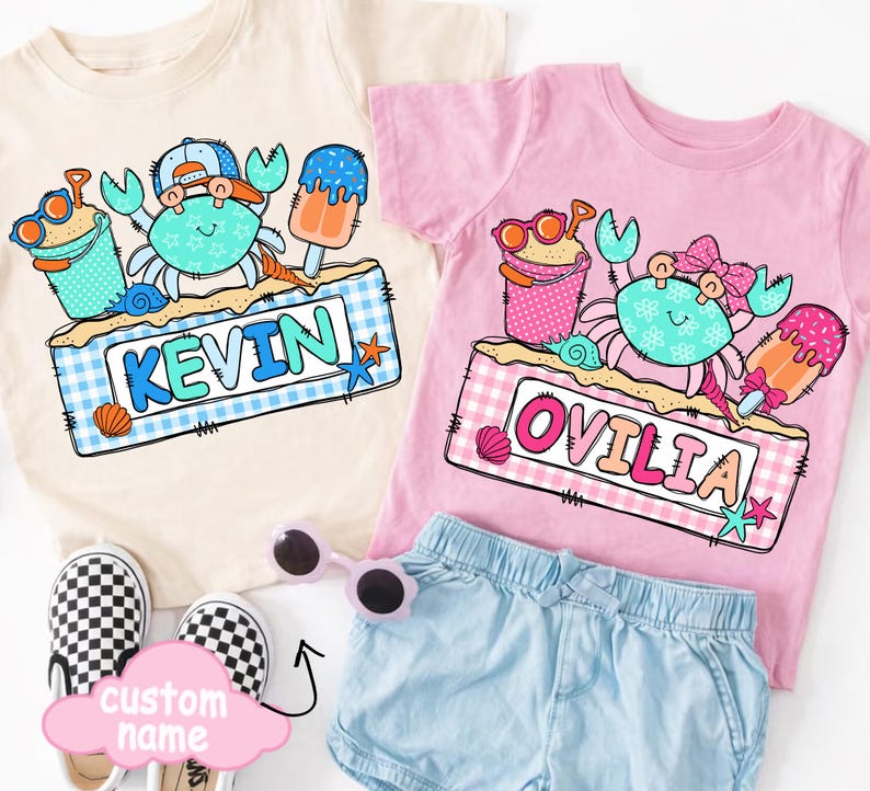 May include: Two children's t-shirts, one cream and one pink, featuring crab designs with sunglasses, ice cream, and the names "KEVIN" and "OVILIA". The shirts are paired with denim shorts and checkered slip-on shoes. A pink cloud-shaped sign says "custom name".