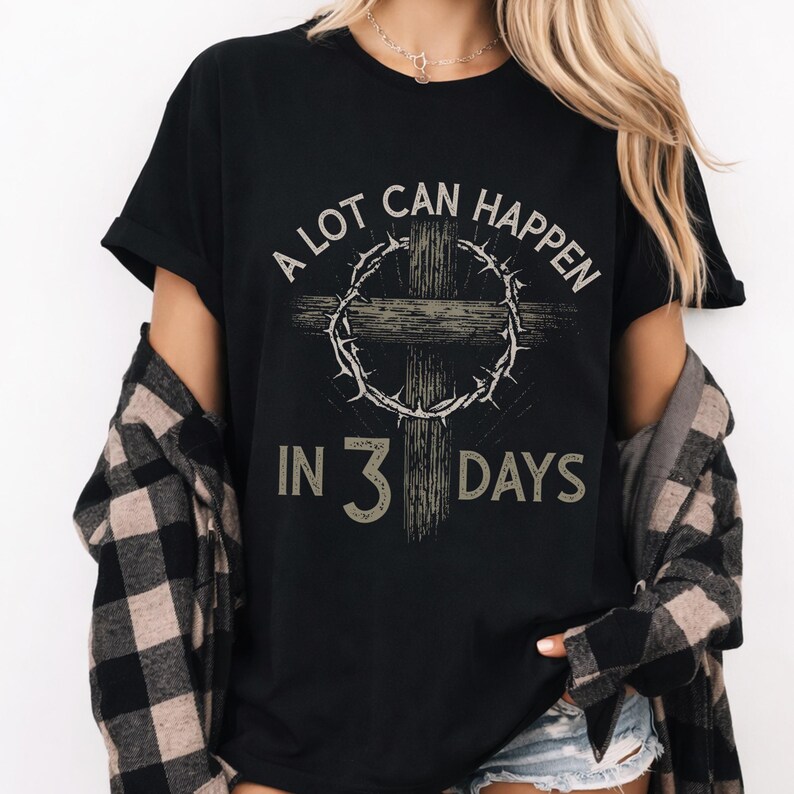 Puede incluir: Camiseta negra con el texto "A LOT CAN HAPPEN IN 3 DAYS" en una fuente desgastada. El dise&ntilde;o presenta una cruz y una corona de espinas. La camiseta es de estilo cuello redondo cl&aacute;sico.
